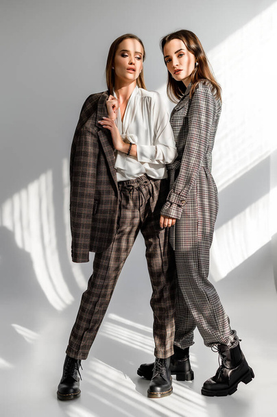 Two girls in a trouser suit and a check overalls on a white background - Foto, Bild