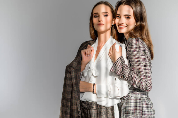 Two girls in a trouser suit and a check overalls on a white background - Foto, afbeelding