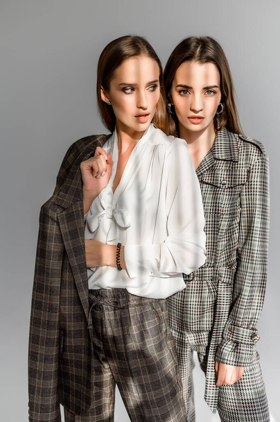Two girls in a trouser suit and a check overalls on a white background - Fotó, kép
