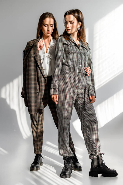 Two girls in a trouser suit and a check overalls on a white background - Fotografie, Obrázek