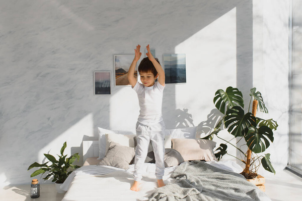 Happy kid in pajama jumping on the bed and having fun in the morning. - Fotoğraf, Görsel