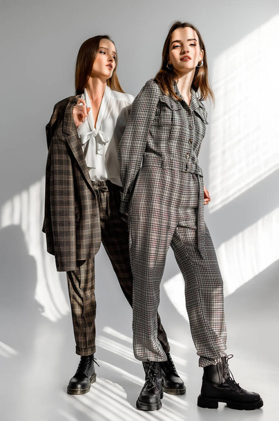 Two girls in a trouser suit and a check overalls on a white background - 写真・画像