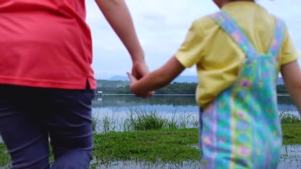 Moeder geniet van haar kind. Gelukkig Aziatisch meisje heeft plezier aan het meer. Gelukkige familie die buiten tijd doorbrengt in de groene natuur. Reizen op vakantie.  - Video
