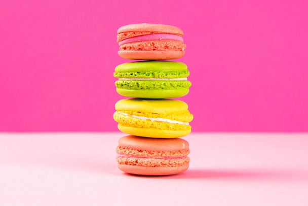 Multi-colored macaroons stand in a pile on a pink table. Close-up - Valokuva, kuva
