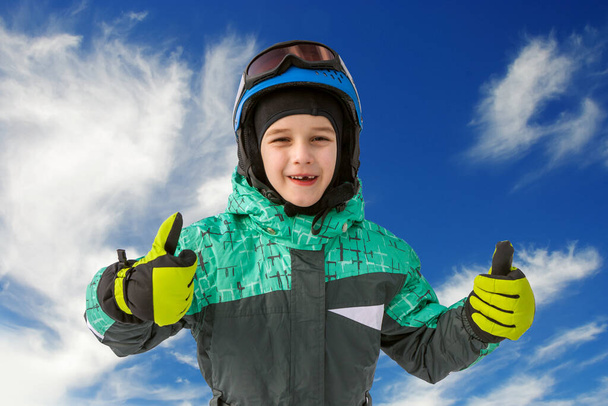 little boy on mountains in ski helmet with fallen first tooth - Фото, изображение