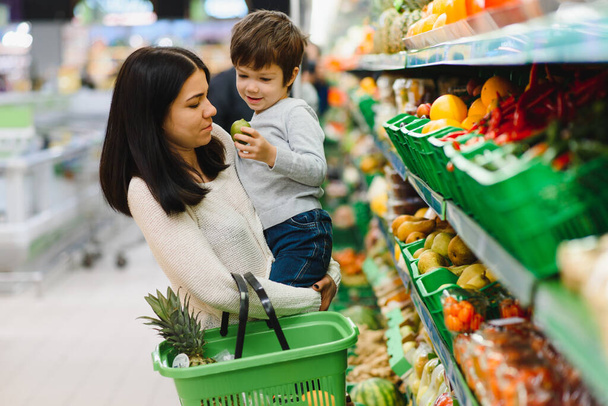 niño y mujer durante las compras familiares con carrito en el supermercado - Foto, imagen
