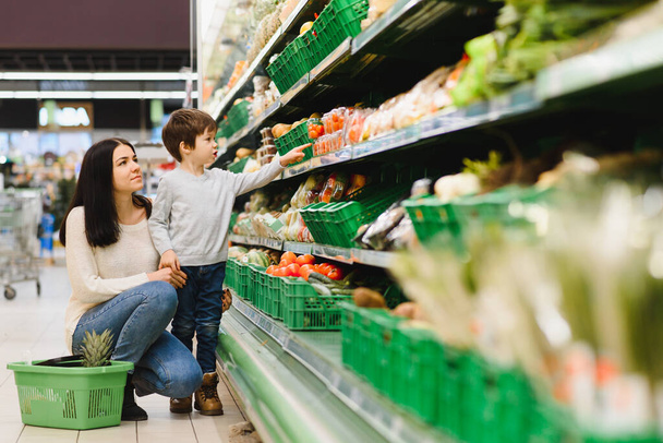 Young mother with her little baby boy at the supermarket. Healthy eating concept - 写真・画像