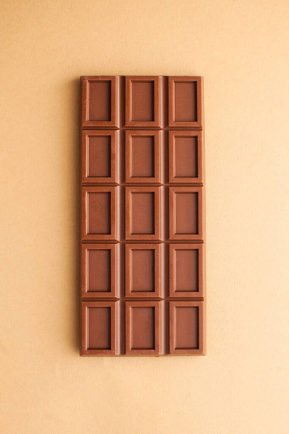 A bar of milk chocolate on a brown background top view. The concept of minimalism. - Fotoğraf, Görsel