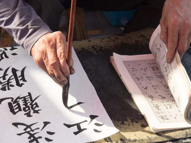 Каллиграф, пишущий от руки китайскую каллиграфию
 - Фото, изображение