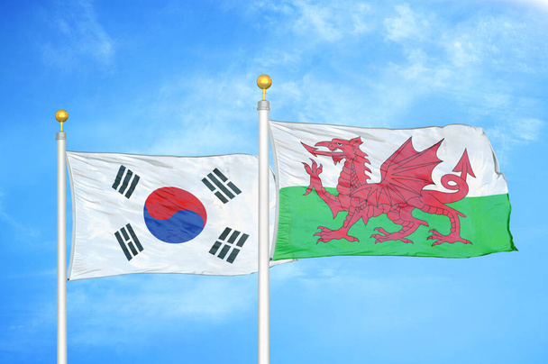 Jižní Korea a Wales dvě vlajky na vlajkových stožárech a modrá oblačná obloha pozadí - Fotografie, Obrázek