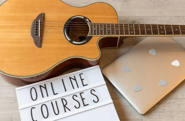 Gitar, penaları olan dizüstü bilgisayar ve online gitar derslerine örnek olması için "online kurslar" yazılı beyaz tahta - Fotoğraf, Görsel
