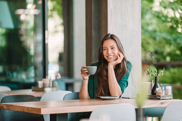 Schöne Frau beim Frühstück im Café im Freien. Glückliche junge Stadtfrau trinkt Kaffee - Foto, Bild