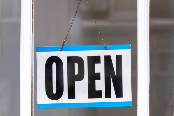 Open sign in a shop window - polite, friendly, calm and businesslike in blue - Photo, Image