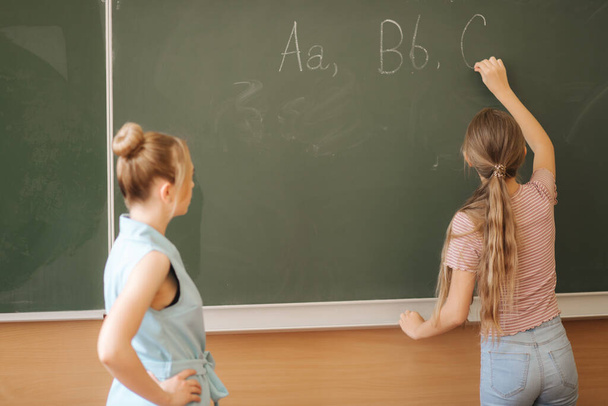 教室の黒板に何かを書く女子高生 - 写真・画像