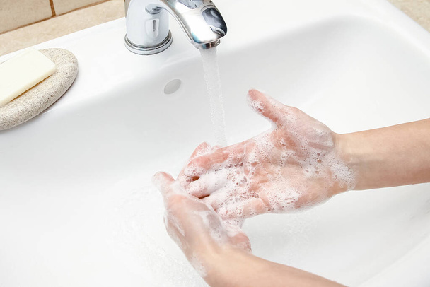Hände mit Seife werden unter dem Wasserhahn mit Wasser gewaschen. Säubern Sie sich von Infektionen, Schmutz und Viren. Zu Hause oder im Krankenhaus Waschung Büro. - Foto, Bild