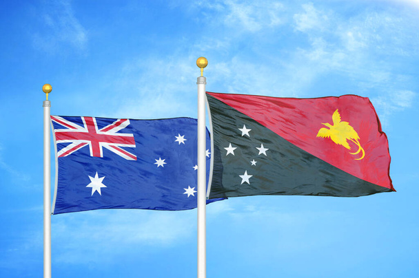 Αυστραλία και Παπούα Νέα Γουινέα δύο σημαίες σε κοντάρια σημαίας και φόντο μπλε συννεφιασμένο ουρανό - Φωτογραφία, εικόνα