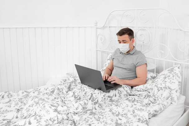 male freelancer in mask work home in bedroom. - Foto, Bild