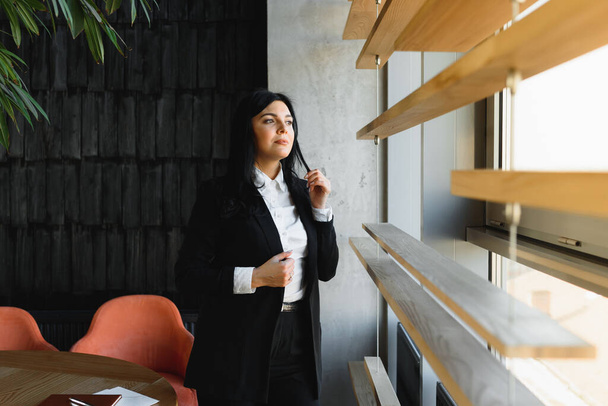 Smiling likable sincere and charming business woman financial executive type portrait inside commercial building. stylish brunette business woman in office - Photo, Image