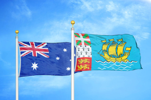 Austrálie a Saint Pierre a Miquelon dvě vlajky na vlajkových stožárech a modrá oblačná obloha pozadí - Fotografie, Obrázek