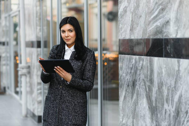 Zakenvrouw werken aan digitale tablet outdoor over gebouw achtergrond - Foto, afbeelding