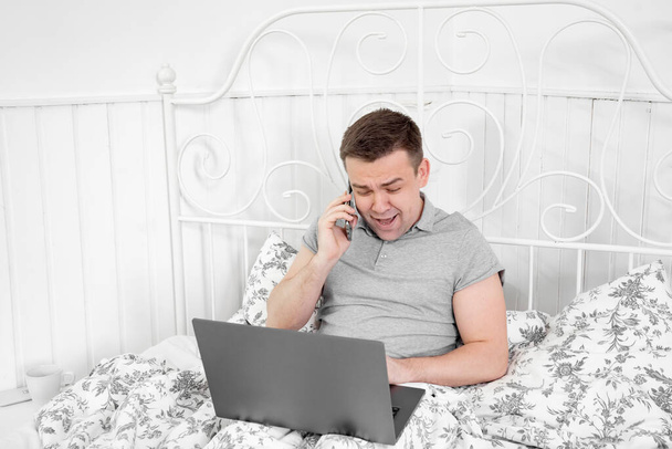 male freelancer swears on phone in bed. stay home. - Foto, Bild