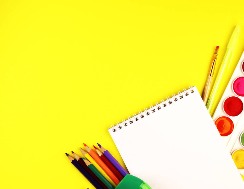 School stationery on a yellow background, top view. paint, Notepad, and colored pencils - Foto, immagini