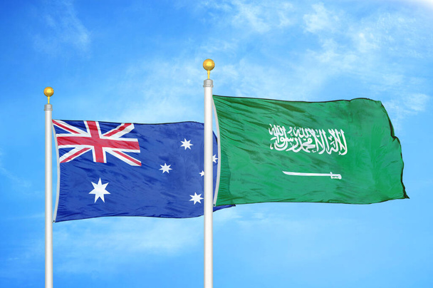 Australië en Saoedi-Arabië twee vlaggen op vlaggenmasten en blauwe bewolkte lucht achtergrond - Foto, afbeelding