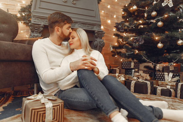 Beautiful couple sitting at home near christmas tree - 写真・画像