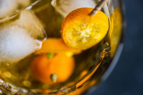 Bril whisky met ijs en kumquat fruit op stenen ondergrond met kopieerruimte - Foto, afbeelding