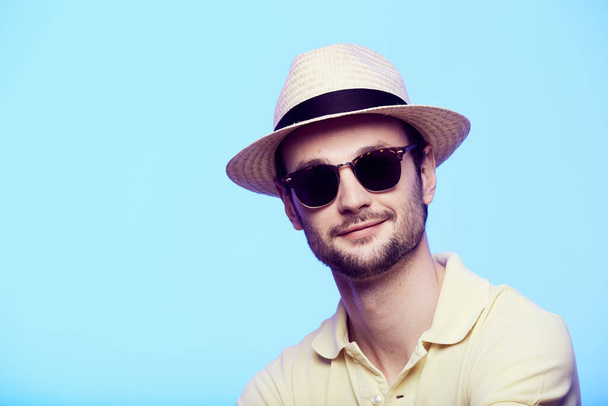 Closeup portrait of awesome hipster wearing fedora hat with intense look at camera. Headshot over blue studio background. - Fotó, kép