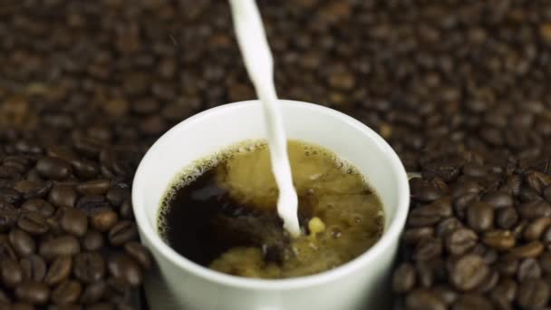 Milch in Kaffeetasse gießen, natürliche Bohnen Hintergrund. Schwungvolles Tagesstart-Konzept - Filmmaterial, Video