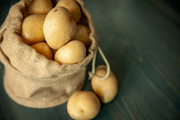 Patatas en saco sobre fondo rústico de madera sobre ventanas suaves comida ligera vintage - Foto, Imagen