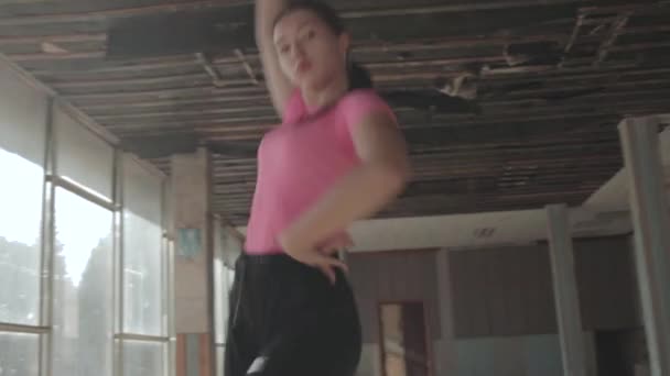 Γυναίκα κλώση χορού σε εγκαταλελειμμένο αίθουσα με πανοραμική παράθυρα, χαμηλό σημείο, χειρός κάμερα - Πλάνα, βίντεο