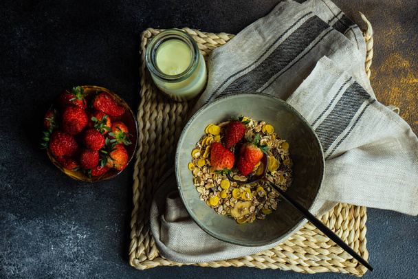 Gesundes Frühstückskonzept mit Haferflocken, frischen Erdbeeren und Joghurt auf Steinhintergrund mit Kopierfläche - Foto, Bild