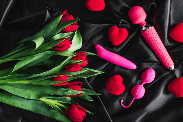 Various sex toys set on a black background. Advertising a sex shop. The view from the top. Spring. Tulips - Photo, Image