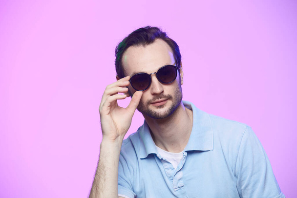 Studio shot of handsome man wearing sunglasses over pink background. - Fotó, kép