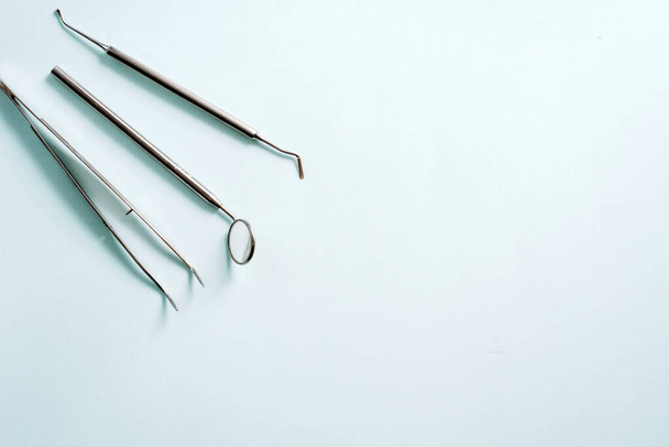 Стоматологические инструменты на синем фоне. Зеркало и пинцет, концепция лечения зубов
. - Фото, изображение