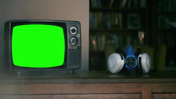Рука піднімає маску "Обличчя респіратора" і ретро-телевізор з зеленим екраном. Дим задній план. Ви можете замінити зелений екран кадрами або уявити собі, що ви хочете з ефектом Кітінга в After Effects..  - Кадри, відео