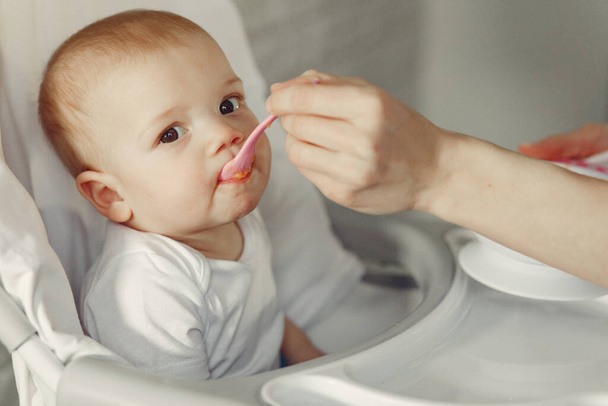 Mother feeds the little baby in a kitchen - Valokuva, kuva