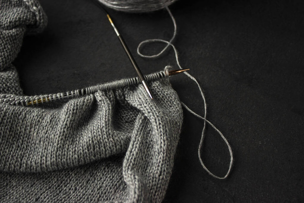 Knitting on silver thread needles lies on a dark background. - Photo, Image