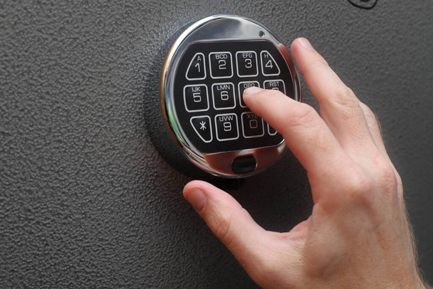 Hand entering combination on a digital lock to open a safe. - Photo, Image