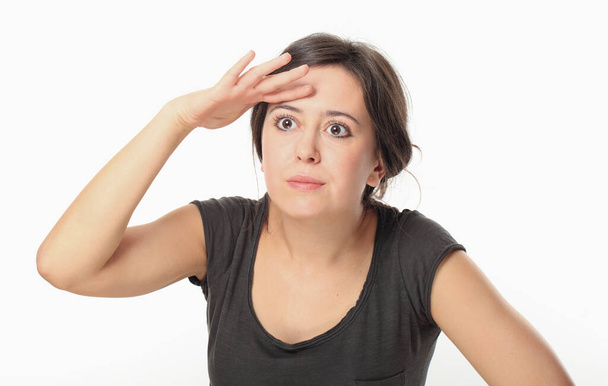 Young woman in T-shirt covering her eyes to search for something - Photo, image