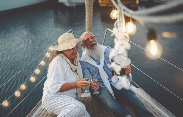 Senior couple toasting champagne while taking selfie on sailboat vacation - Ευτυχισμένοι ώριμοι άνθρωποι που διασκεδάζουν γιορτάζοντας την επέτειο του γάμου τους στο ταξίδι - Αγάπη σχέση και ταξιδιωτικό τρόπο ζωής - Φωτογραφία, εικόνα