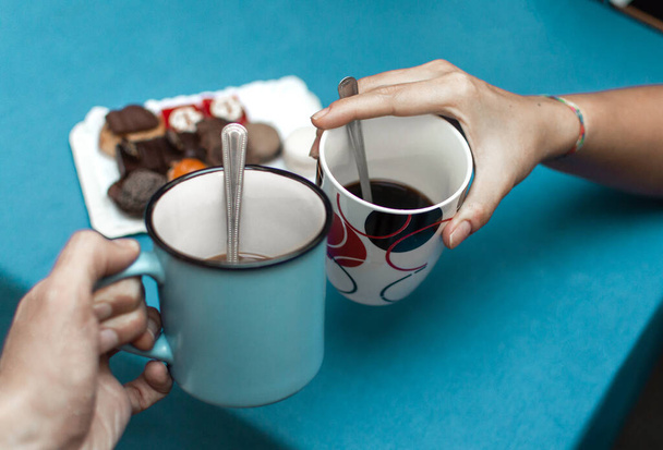 Ystävät kohottavat maljan kahvikupillisella ennen kuin syövät makeita leivonnaisia. Kofeiiniriippuvainen
. - Valokuva, kuva