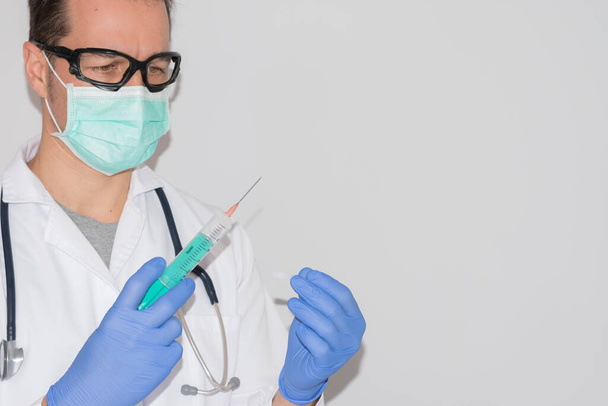 Arzt mit medizinischer Maske und Schutzbrille, die die Spritze hält und weiß isoliert - Foto, Bild