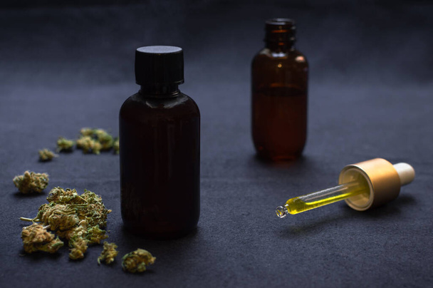 Organic CBD oil or tincture make with cannabis on black background. Medical marijuana product, weed buds and dropper. - Fotó, kép
