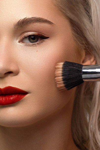 Half a beauty portrait with beautiful fashionable evening make-up, black smoky eyes and extremely long eyelashes. red lipstick on the lips. Cosmetology and spa facial skin care - Photo, Image