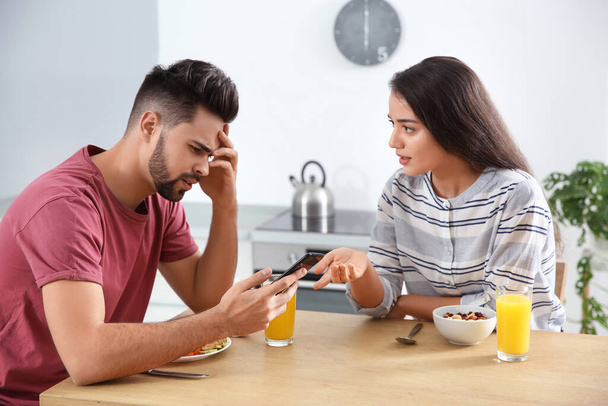 Young man with smartphone ignoring his girlfriend at home - Foto, Imagen