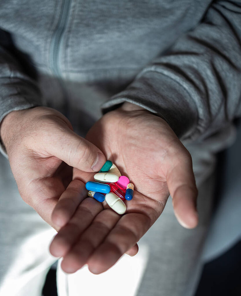 Un homme tient diverses pilules multicolores dans ses mains. Gros plan. Le concept de protection de la santé et de prévention des maladies associées à la grippe et au coronovirus. Soulager la douleur
 - Photo, image