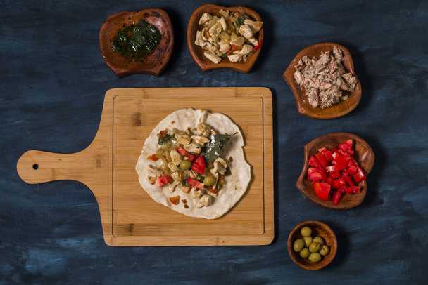 A piadina with chicken and other vegetables on a blue table. - Photo, image